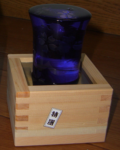 A glass of sake inside a wooden box which is also filled with sake