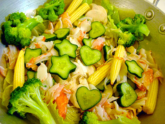 A bowl of salad containing star-shaped and heart-shaped cucumber slices