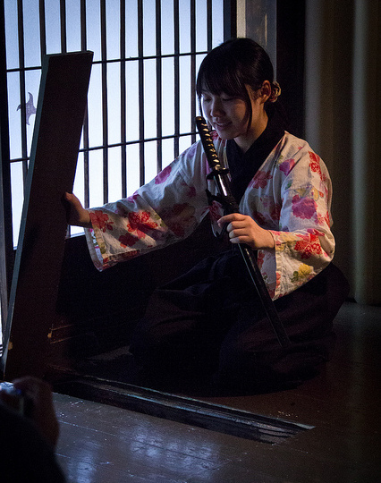 A woman removing a sword from its hiding place at Iga Ninja Museum in Mie Prefecture