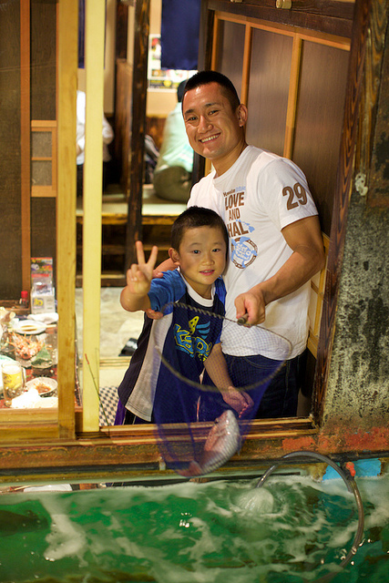 A boy and his father, with the fish they have just caught and are about to eat, at a Zauo restaurant