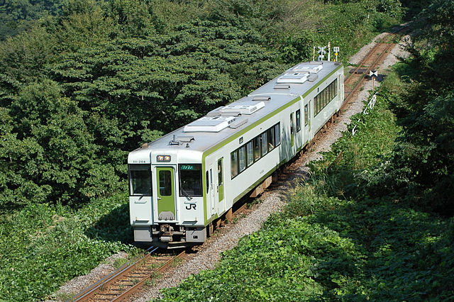 A diesel passenger train passing through countryside on the Hachiko Line in Japan