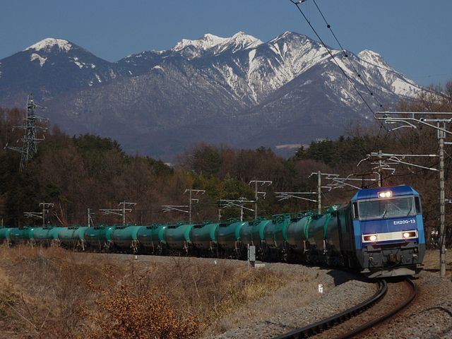 An engine pulling a train of tankers in front of snow-covered mountains in Japan