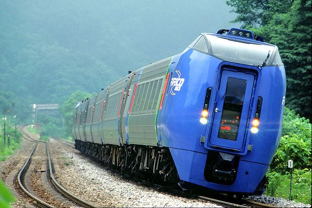 A tilting train in Hokkaido leans to the left as it prepares to go around a bend