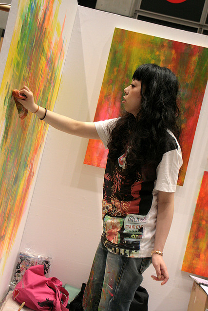 A woman works on a bright coloured abstract painting at Design Festa in Tokyo