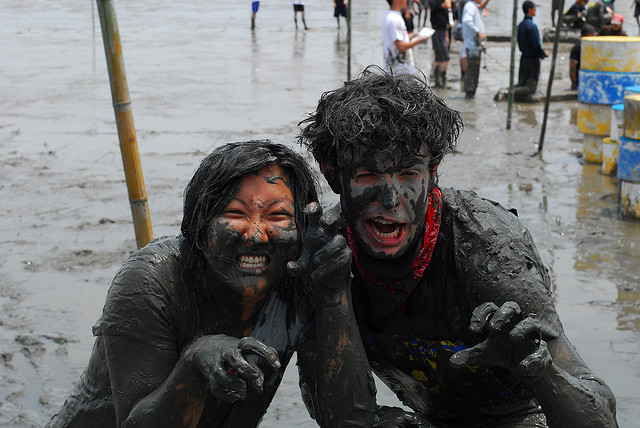 A man and a woman covered in mud and making faces, at the Kashima Gatalympics