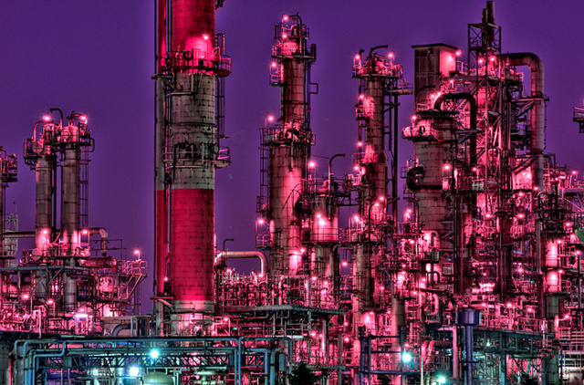 An illuminated industrial complex against a purple sky