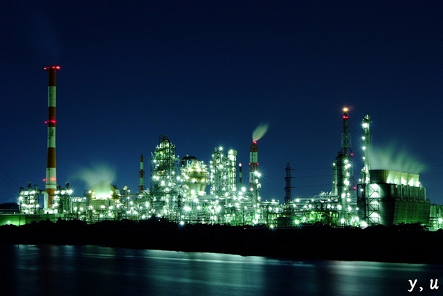 Steam rises from a brightly-lit petrochemical plant