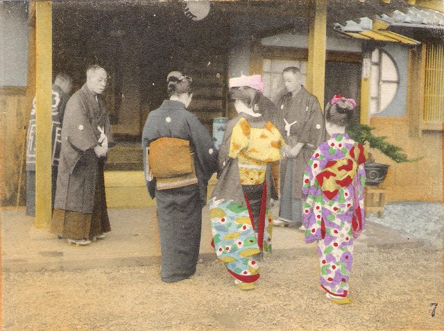 A bride accompanied by two women arrives at a house where three men are waiting. All six people are wearing kimonos