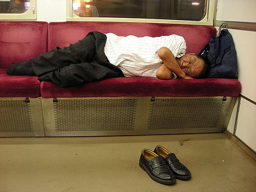 A man sleeping on a bench seat on a train