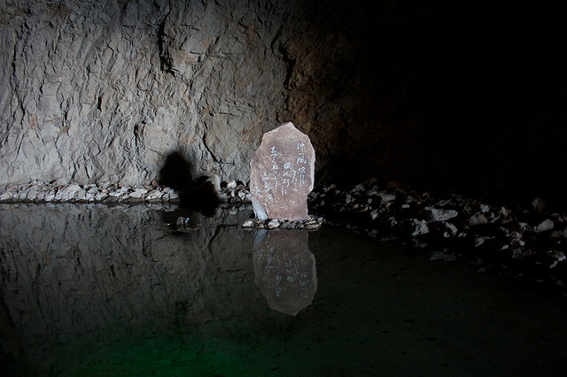 A stone with writing on it in a pool of water in the Iwaya Caves on Enoshima Island