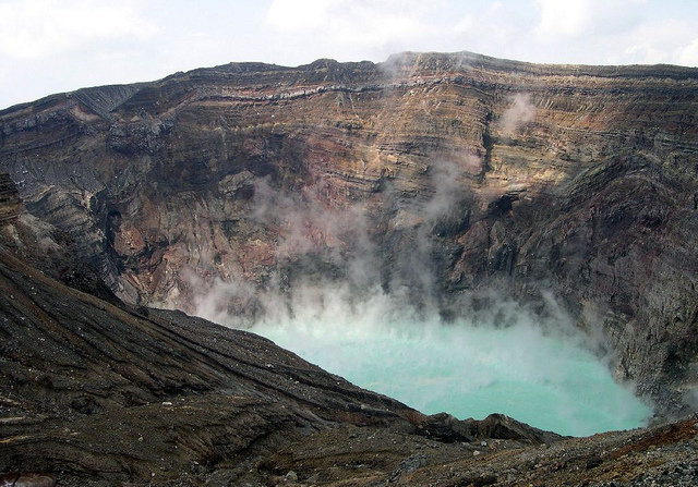 A steaming blue-green lake in the crater of Nakadake volcano