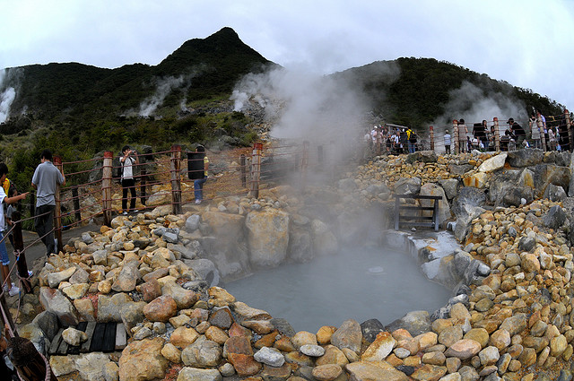 A steaming pool of sulphurous water and one of the summits of Hakone Volcano
