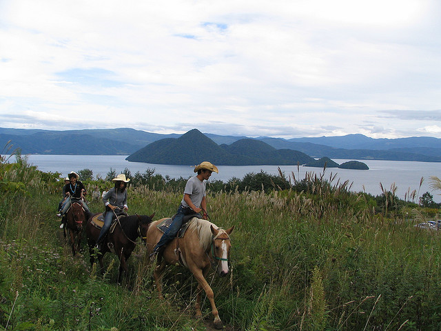 People riding horses near the shore of Lake Toya
